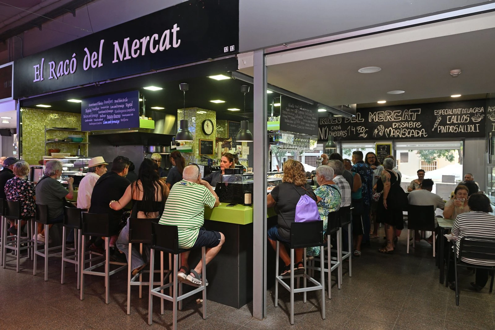 La barra i les taules d’El Racó del Mercat, amb el rètol de les parades 12 i 13